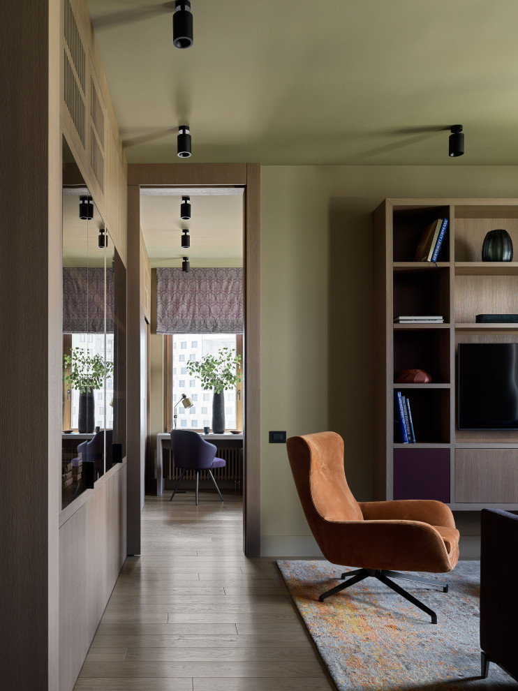 Imagen de biblioteca en casa abierta contemporánea grande con paredes marrones, suelo de madera en tonos medios, televisor colgado en la pared y suelo marrón