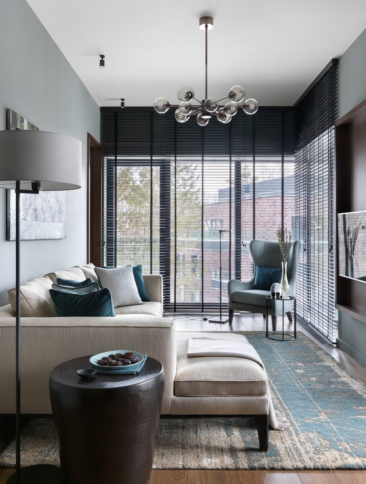 Стильный дизайн: изолированная гостиная комната среднего размера в современном стиле с серыми стенами, паркетным полом среднего тона, телевизором на стене и коричневым полом без камина - последний тренд