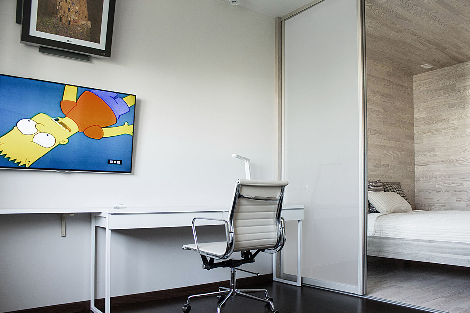 Foto på ett litet minimalistiskt vardagsrum, med vita väggar och en väggmonterad TV
