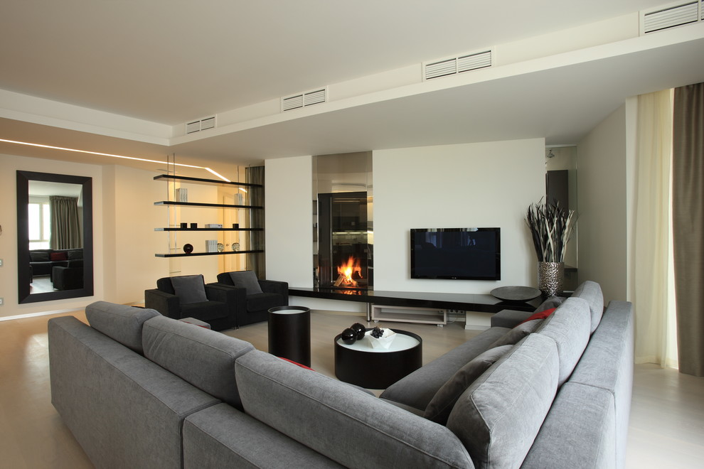 Стильный дизайн: парадная, открытая гостиная комната в современном стиле с белыми стенами, телевизором на стене и двусторонним камином - последний тренд