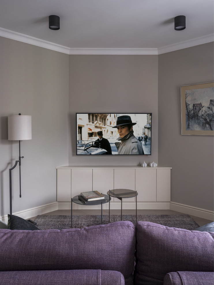 Klassisk inredning av ett mellanstort allrum med öppen planlösning, med ett finrum, grå väggar, ljust trägolv, en väggmonterad TV och grått golv