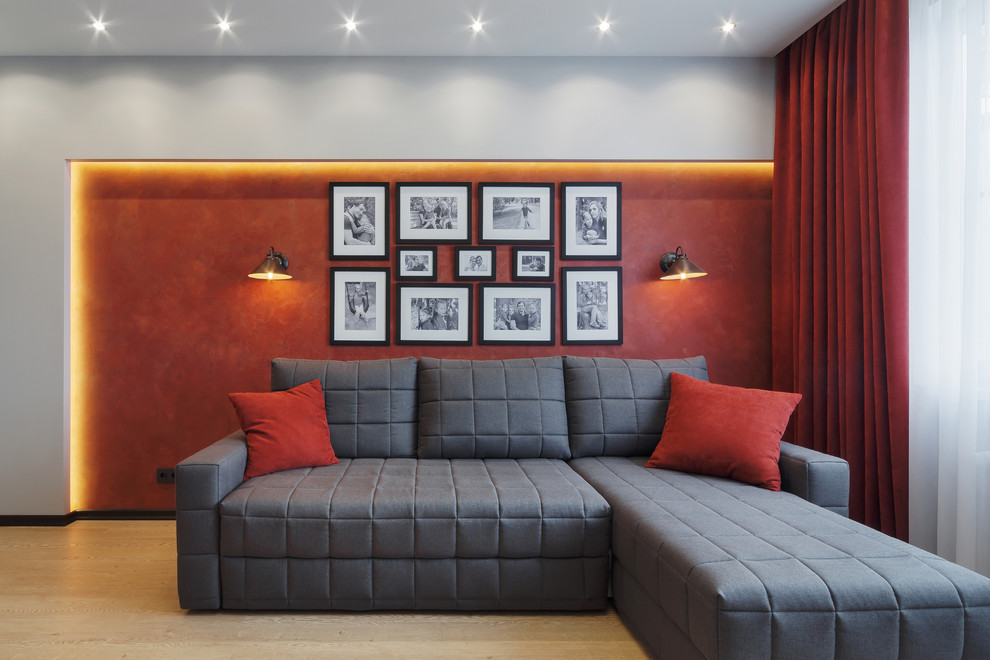 Cette image montre un salon design de taille moyenne et fermé avec un mur gris, un sol en bois brun, un téléviseur fixé au mur et un sol beige.