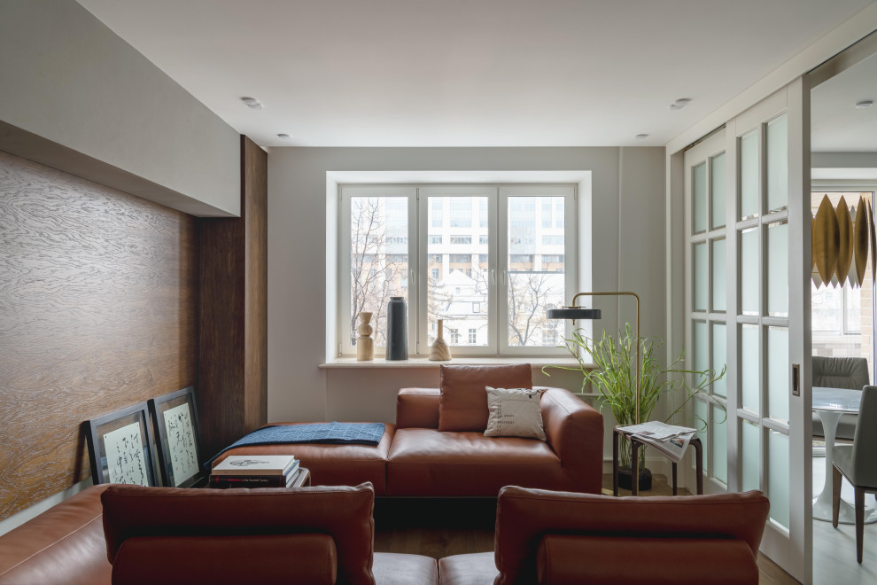На фото: открытая гостиная комната среднего размера в стиле неоклассика (современная классика) с белыми стенами, темным паркетным полом, коричневым полом и панелями на стенах без телевизора с