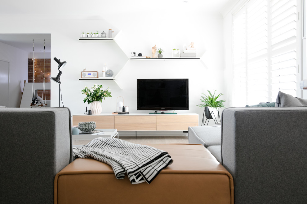 Пример оригинального дизайна: открытая гостиная комната среднего размера в скандинавском стиле с белыми стенами, паркетным полом среднего тона и отдельно стоящим телевизором без камина