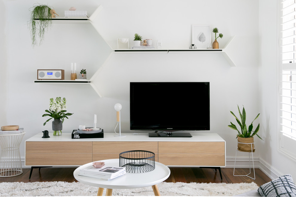 Inredning av ett nordiskt mellanstort allrum med öppen planlösning, med vita väggar, mellanmörkt trägolv och en fristående TV