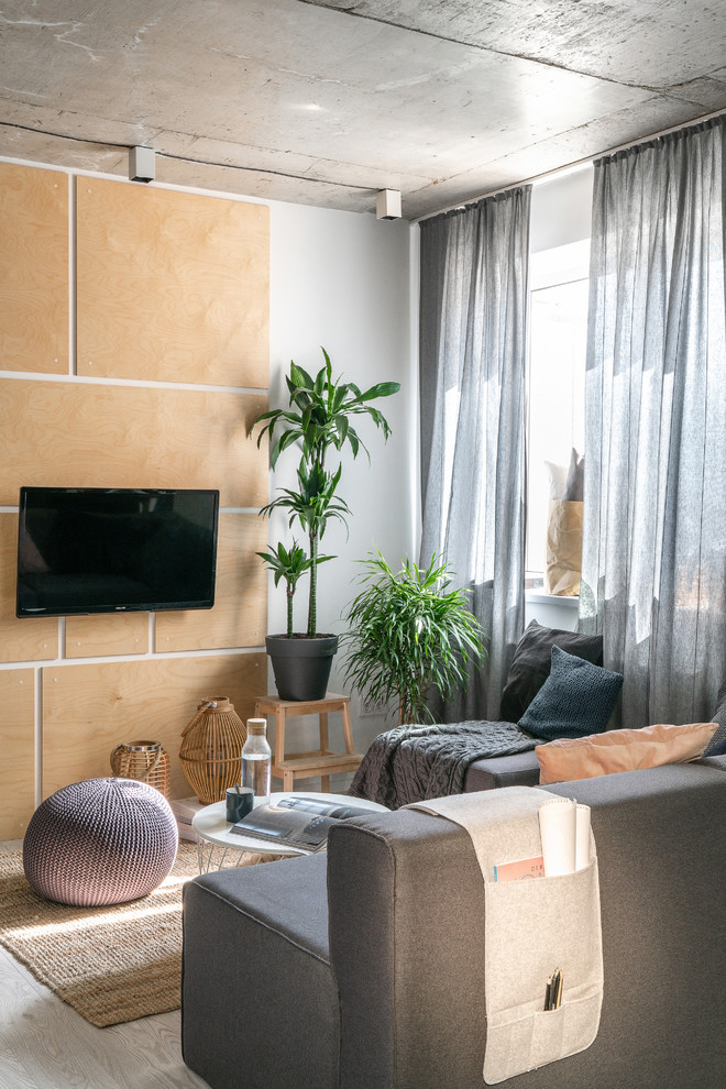 На фото: гостиная комната в скандинавском стиле с телевизором на стене