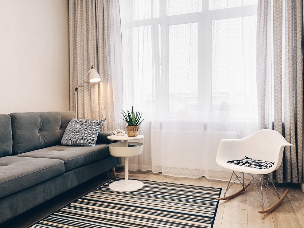 Immagine di un soggiorno nordico di medie dimensioni con pareti beige, pavimento in laminato, TV autoportante e pavimento marrone