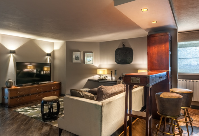 На фото: открытая гостиная комната среднего размера в стиле лофт с домашним баром, серыми стенами, полом из ламината, отдельно стоящим телевизором и коричневым полом с