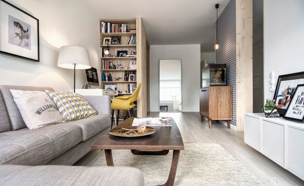 Immagine di un piccolo soggiorno nordico aperto con libreria, pareti bianche e pavimento in laminato
