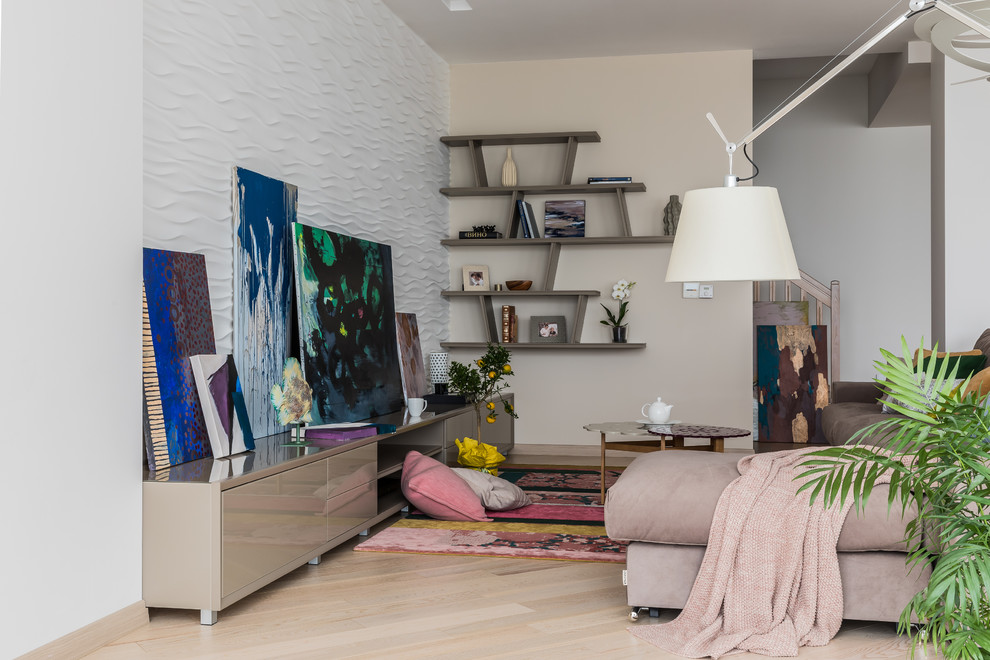 Modelo de salón contemporáneo sin chimenea y televisor con paredes blancas, suelo de madera clara y suelo beige