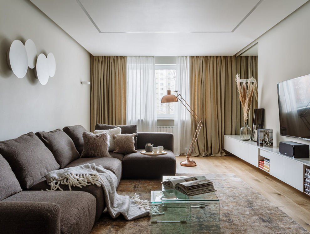 Cette image montre un salon design de taille moyenne et fermé avec un mur beige, parquet clair, un sol beige et un téléviseur fixé au mur.