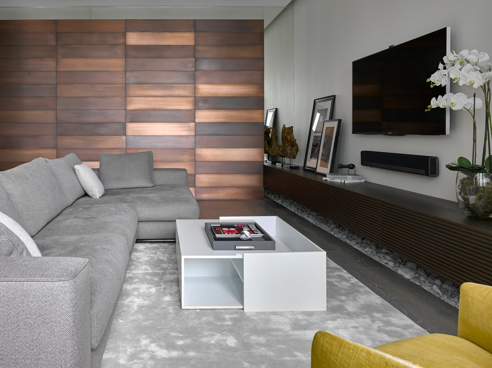 Modelo de salón abierto actual con suelo de madera oscura y televisor colgado en la pared