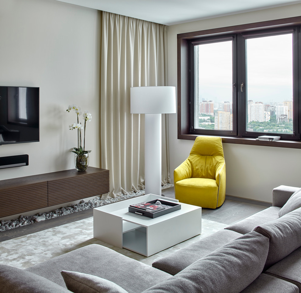 Immagine di un soggiorno contemporaneo aperto con sala formale, pareti bianche, parquet chiaro e TV a parete
