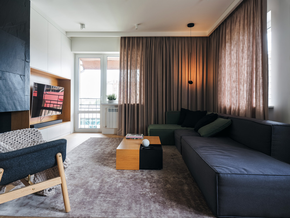 Стильный дизайн: гостиная комната в современном стиле с белыми стенами, светлым паркетным полом, телевизором на стене и бежевым полом - последний тренд