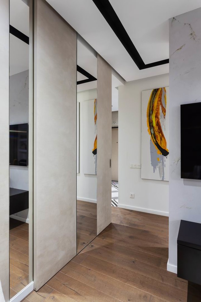 Imagen de salón abierto contemporáneo de tamaño medio con paredes blancas, suelo de madera en tonos medios, televisor colgado en la pared y suelo marrón