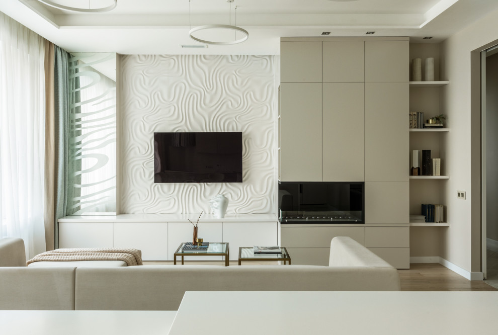 Modern inredning av ett stort allrum med öppen planlösning, med vita väggar, en bred öppen spis, en väggmonterad TV, beiget golv, ljust trägolv och en spiselkrans i metall
