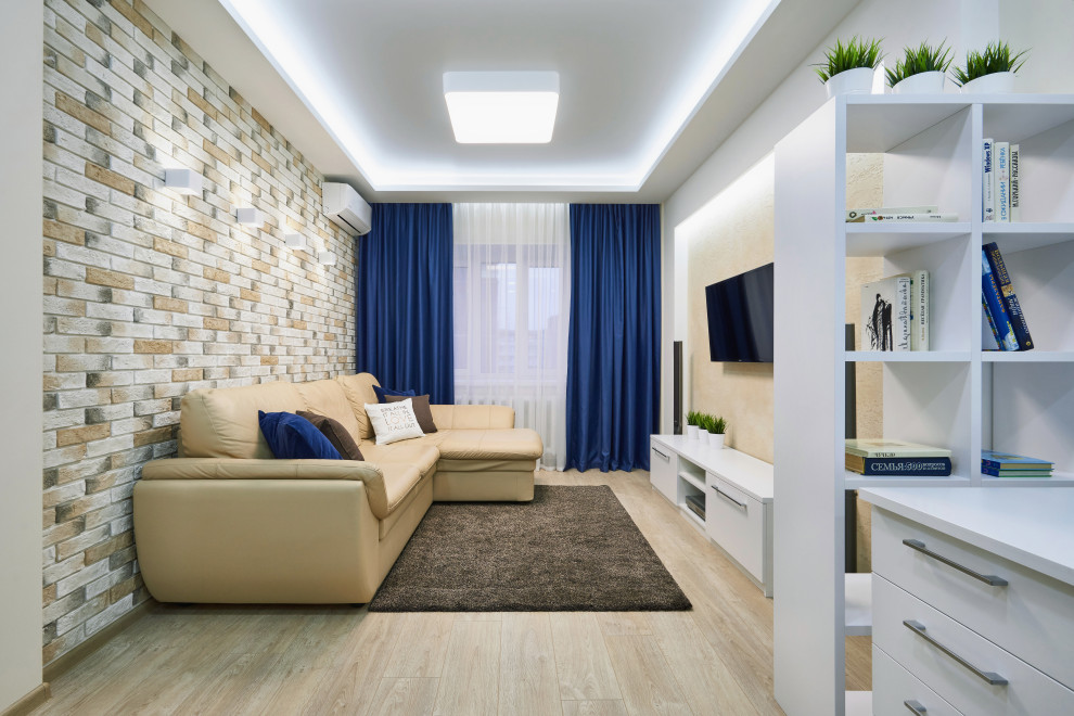 Mid-sized trendy laminate floor, beige floor, tray ceiling and brick wall living room photo in Other with beige walls and a wall-mounted tv
