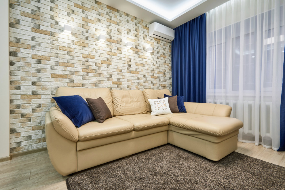 Пример оригинального дизайна: гостиная комната среднего размера в современном стиле с бежевыми стенами, полом из ламината, телевизором на стене, бежевым полом, многоуровневым потолком и кирпичными стенами