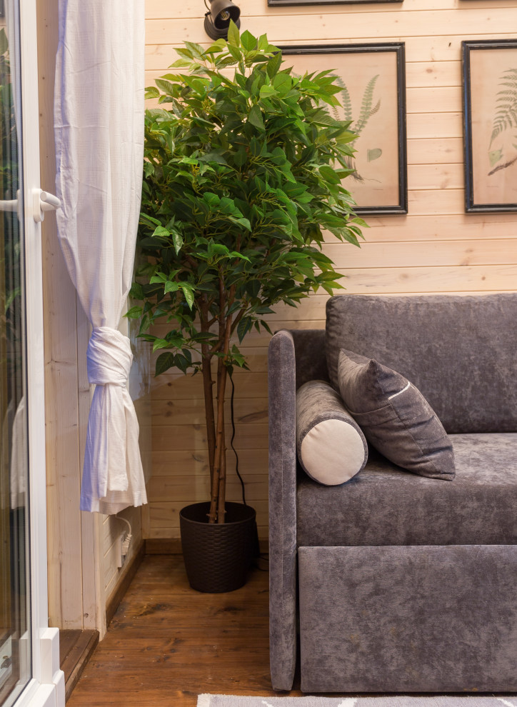 Свежая идея для дизайна: маленькая двухуровневая гостиная комната в скандинавском стиле с белыми стенами, печью-буржуйкой, фасадом камина из металла, телевизором на стене и коричневым полом для на участке и в саду - отличное фото интерьера