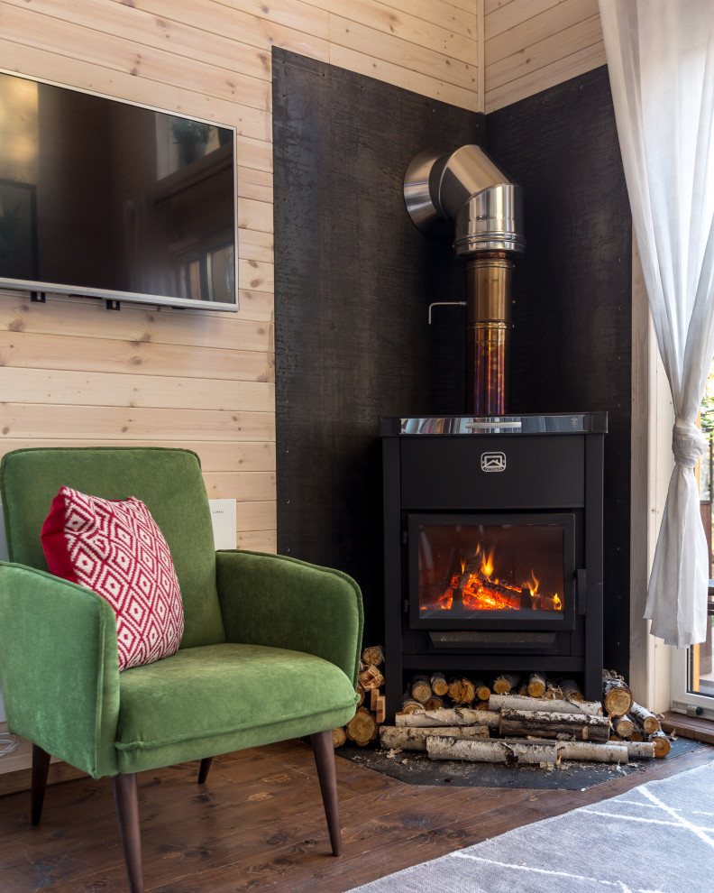 Immagine di un piccolo soggiorno nordico stile loft con pareti bianche, stufa a legna, cornice del camino in metallo, TV a parete e pavimento marrone