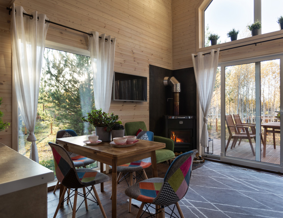 Modelo de salón tipo loft escandinavo pequeño con paredes blancas, estufa de leña, marco de chimenea de metal, televisor colgado en la pared y suelo marrón