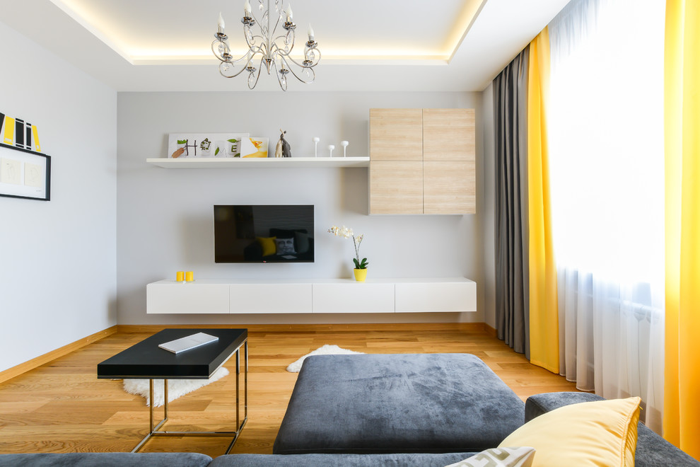 Idée de décoration pour un salon gris et jaune design de taille moyenne et ouvert avec un sol en bois brun, un téléviseur fixé au mur et un mur blanc.