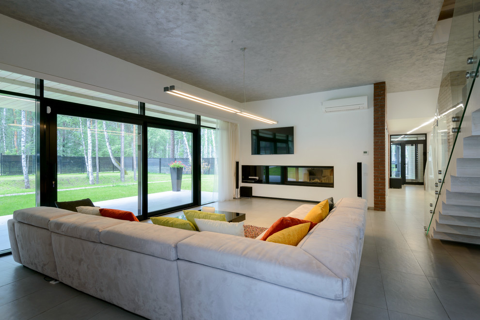 Ejemplo de salón abierto contemporáneo con paredes blancas, suelo de baldosas de porcelana, chimenea lineal, marco de chimenea de metal y televisor colgado en la pared