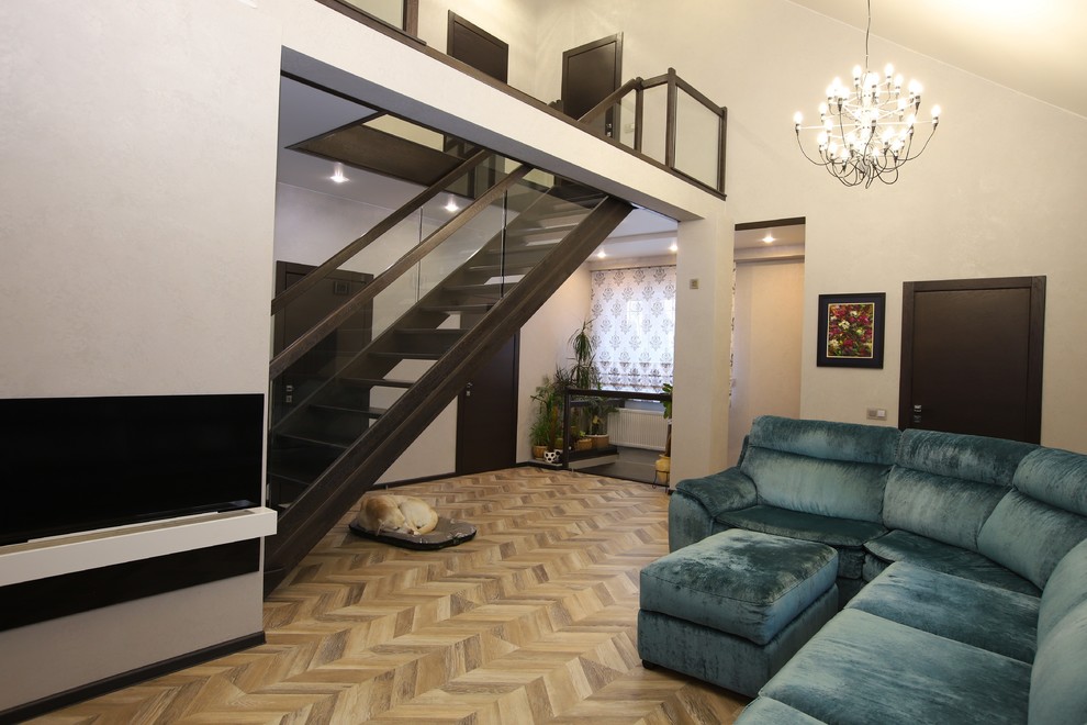 Пример оригинального дизайна: двухуровневая гостиная комната среднего размера в современном стиле с серыми стенами, полом из ламината, подвесным камином, фасадом камина из камня, телевизором на стене и бежевым полом