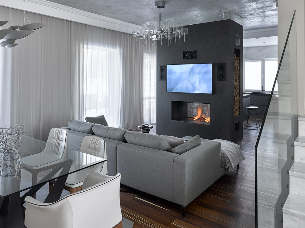 Idee per un soggiorno design aperto con pareti grigie, parquet scuro, pavimento marrone, sala formale, camino bifacciale e TV a parete
