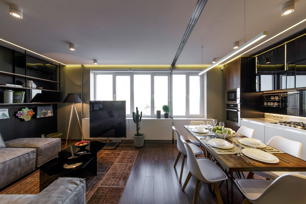 Источник вдохновения для домашнего уюта: изолированная, объединенная гостиная комната среднего размера в современном стиле с черными стенами, полом из ламината, отдельно стоящим телевизором и коричневым полом
