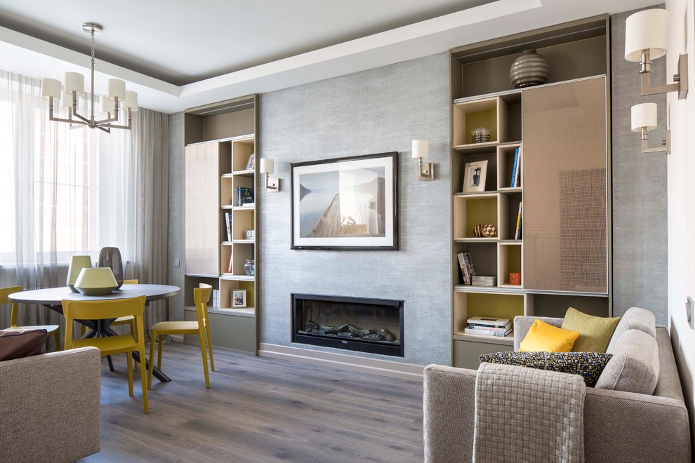 Modelo de salón abierto contemporáneo sin televisor con paredes grises, suelo de madera en tonos medios, marco de chimenea de yeso, suelo marrón y chimenea lineal