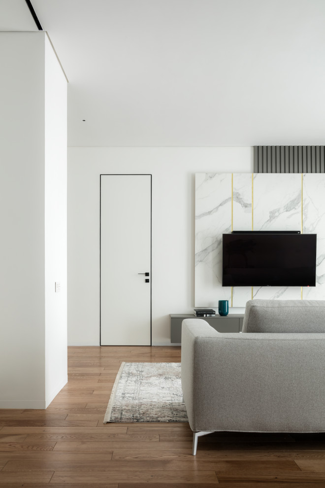 Источник вдохновения для домашнего уюта: серо-белая гостиная комната среднего размера в современном стиле с паркетным полом среднего тона, телевизором на стене, коричневым полом и акцентной стеной