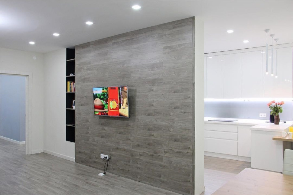 На фото: открытая гостиная комната среднего размера в современном стиле с серыми стенами, полом из ламината, телевизором на стене и коричневым полом