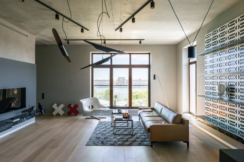 Foto de salón para visitas abierto urbano con paredes grises, suelo de madera en tonos medios, televisor colgado en la pared y suelo marrón