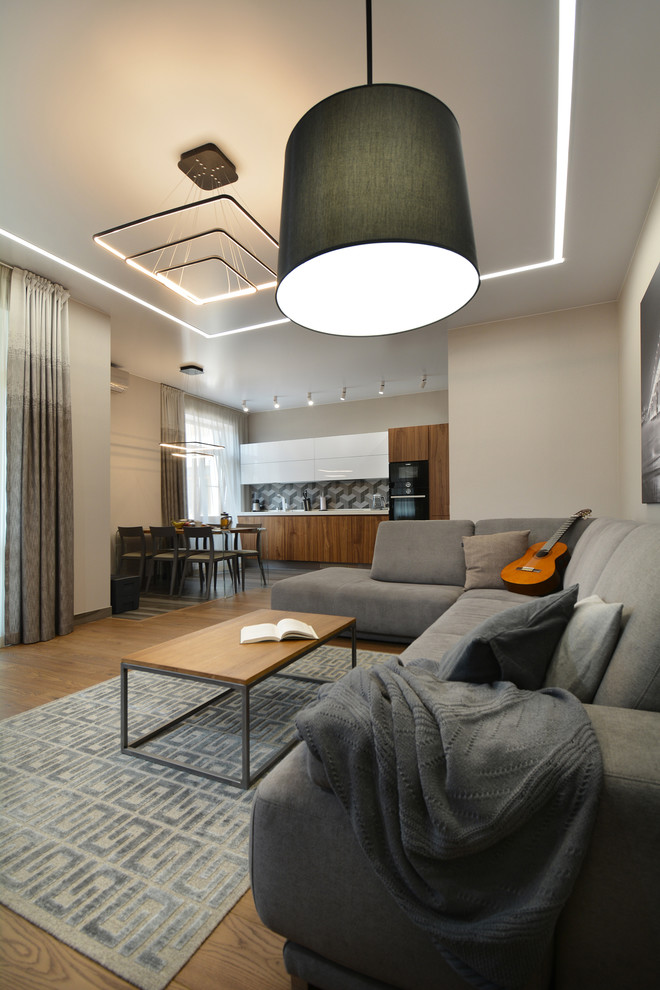 Пример оригинального дизайна: большая открытая гостиная комната в современном стиле с серыми стенами, паркетным полом среднего тона, телевизором на стене и коричневым полом