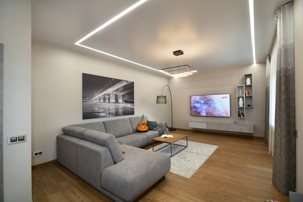 Свежая идея для дизайна: большая открытая гостиная комната в современном стиле с серыми стенами, паркетным полом среднего тона, телевизором на стене и коричневым полом - отличное фото интерьера