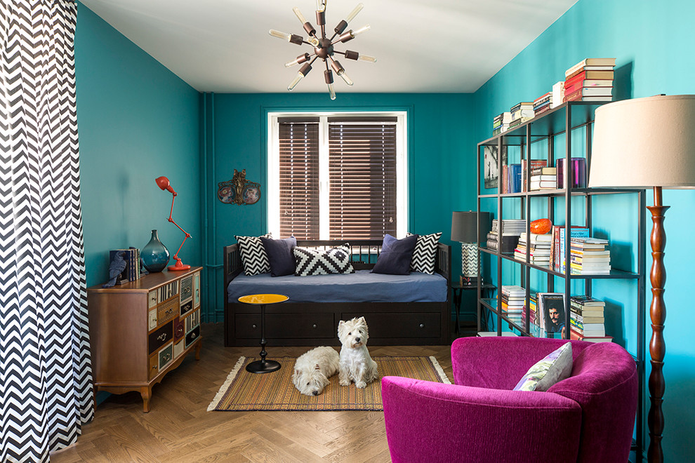Imagen de sala de estar con biblioteca ecléctica con paredes azules, suelo de madera en tonos medios y alfombra