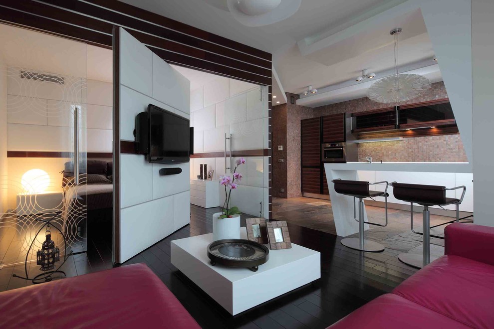 На фото: открытая гостиная комната среднего размера в современном стиле с бежевыми стенами, темным паркетным полом и телевизором на стене