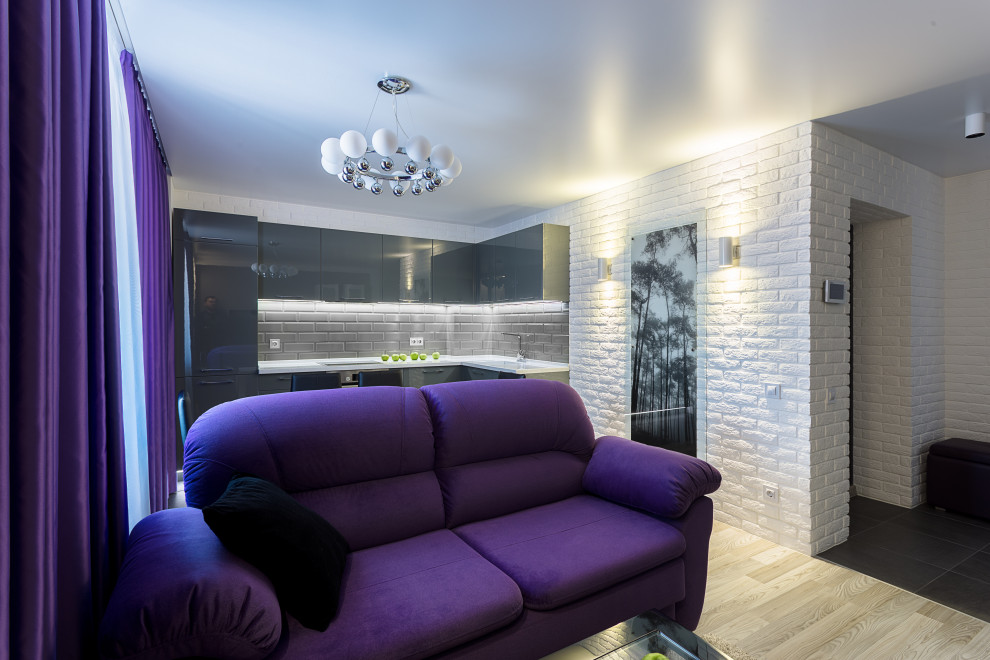 На фото: маленькая объединенная гостиная комната в современном стиле с белыми стенами, полом из ламината, телевизором на стене, серым полом и кирпичными стенами для на участке и в саду с