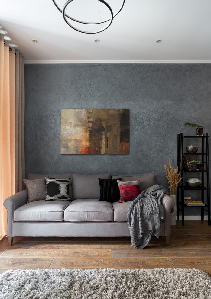 Idée de décoration pour un salon design de taille moyenne et fermé avec un mur gris, sol en stratifié, un téléviseur fixé au mur et un sol marron.