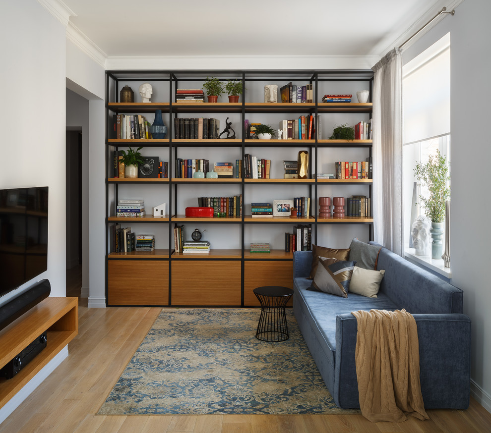 Свежая идея для дизайна: изолированная гостиная комната в современном стиле с с книжными шкафами и полками, светлым паркетным полом, телевизором на стене, синими стенами и коричневым полом - отличное фото интерьера