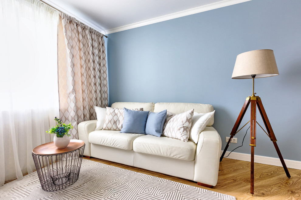 Foto de salón para visitas cerrado moderno de tamaño medio con paredes azules, suelo laminado, televisor independiente y suelo marrón