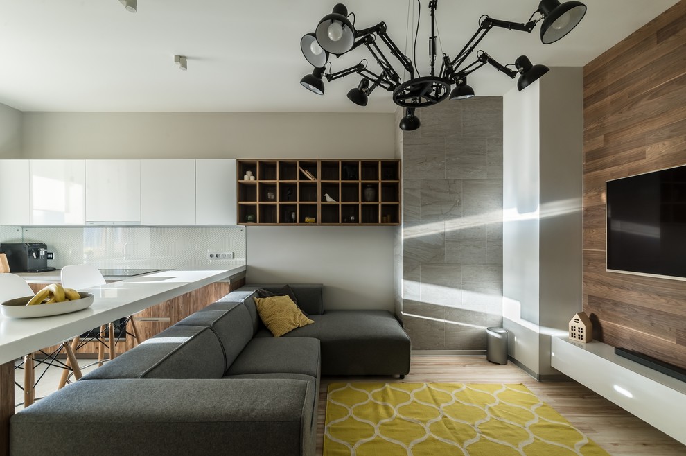 Источник вдохновения для домашнего уюта: открытая гостиная комната в современном стиле с серыми стенами, светлым паркетным полом, телевизором на стене и бежевым полом без камина