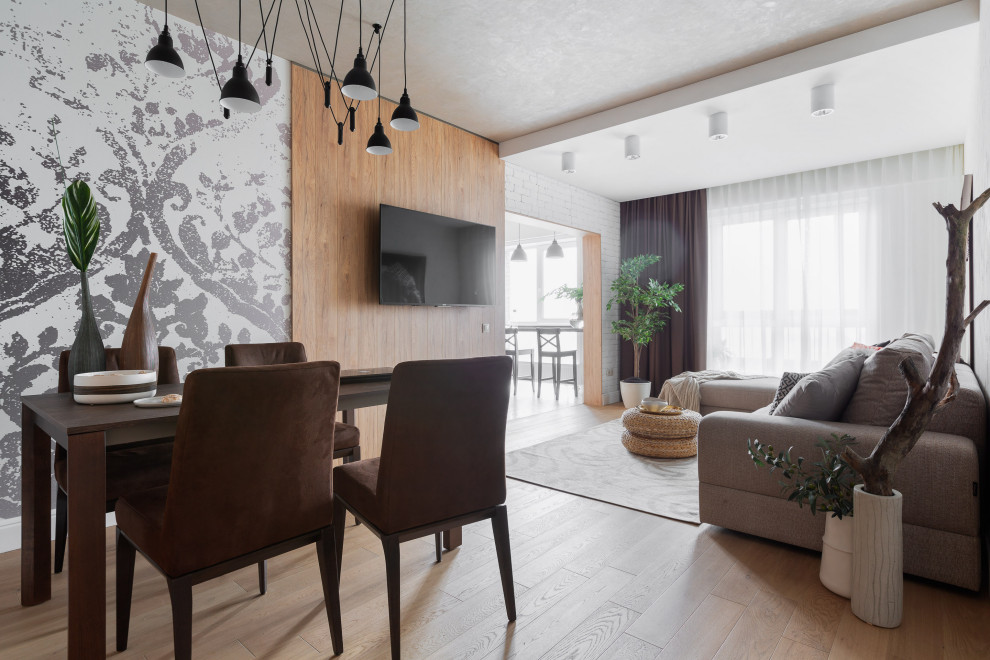 На фото: гостиная комната среднего размера в современном стиле с светлым паркетным полом и телевизором на стене