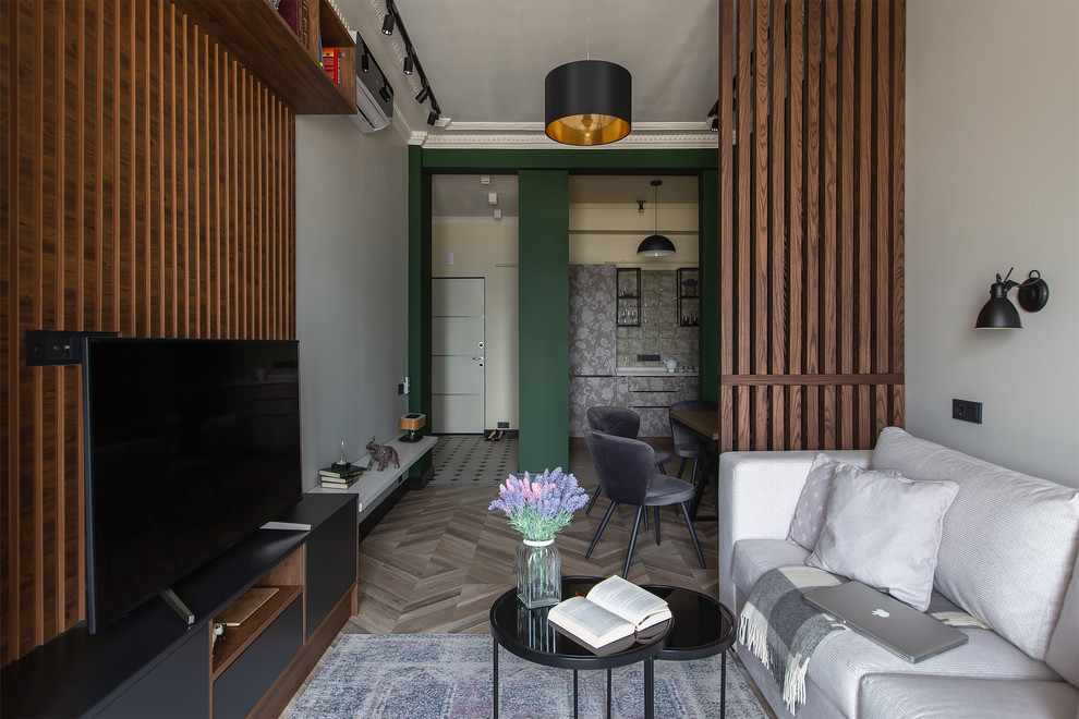 Offenes Modernes Wohnzimmer mit braunem Holzboden, freistehendem TV und beigem Boden in Moskau
