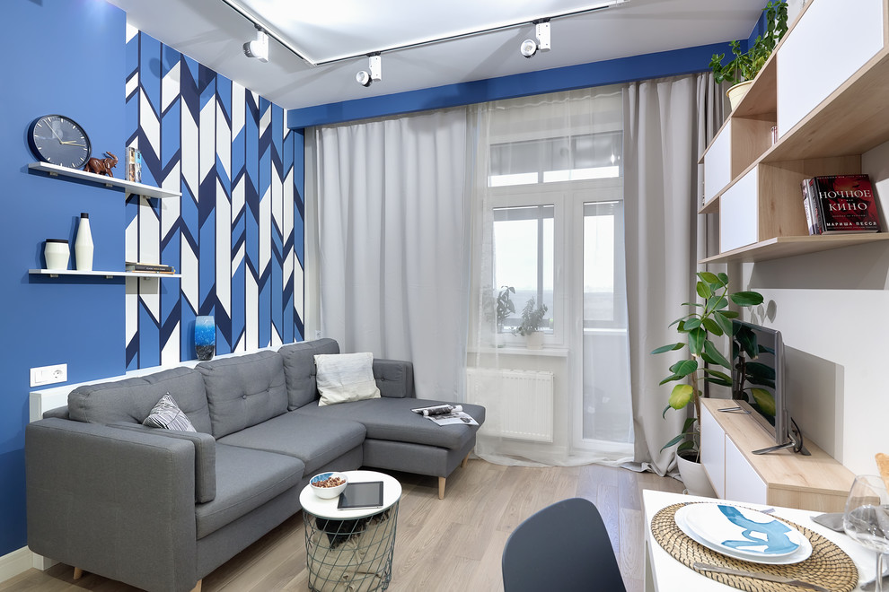Abgetrenntes Modernes Wohnzimmer mit blauer Wandfarbe, hellem Holzboden, freistehendem TV und beigem Boden in Moskau