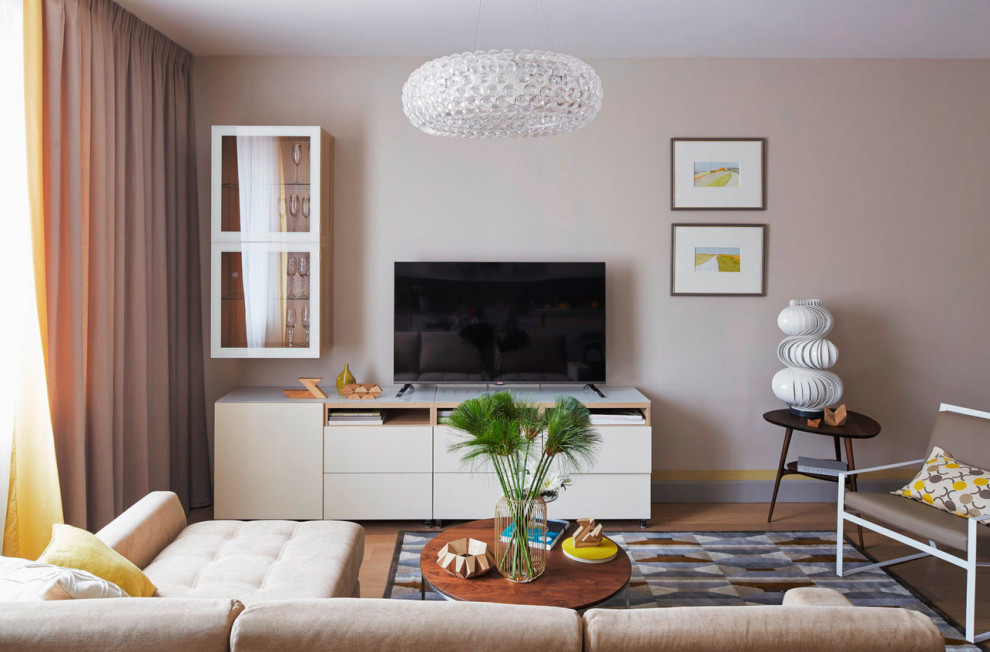 Idee per un soggiorno design di medie dimensioni con pareti beige, pavimento in legno massello medio, TV autoportante e pavimento marrone
