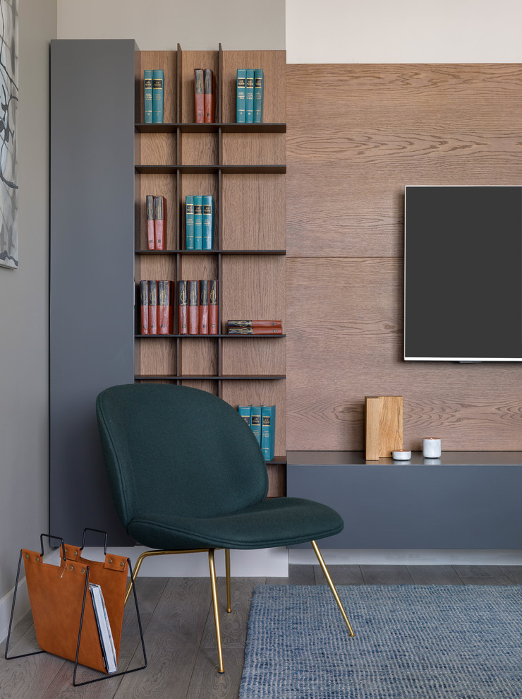 Réalisation d'un grand salon design ouvert avec une bibliothèque ou un coin lecture, un mur gris, un sol en bois brun, un sol gris et un téléviseur fixé au mur.