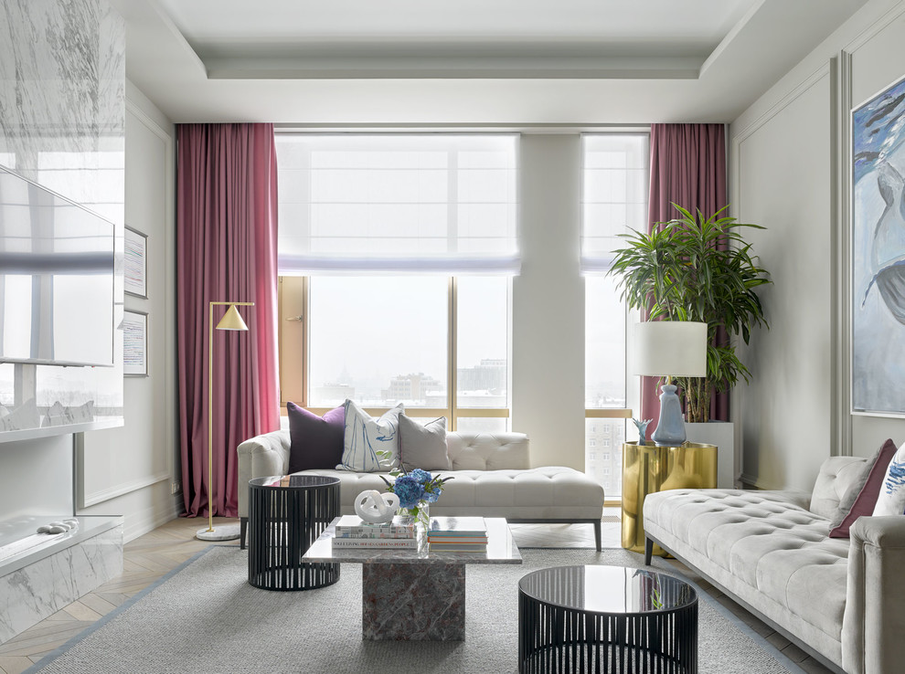 Пример оригинального дизайна: парадная, открытая гостиная комната в стиле неоклассика (современная классика) с серыми стенами, светлым паркетным полом, горизонтальным камином, фасадом камина из камня и телевизором на стене