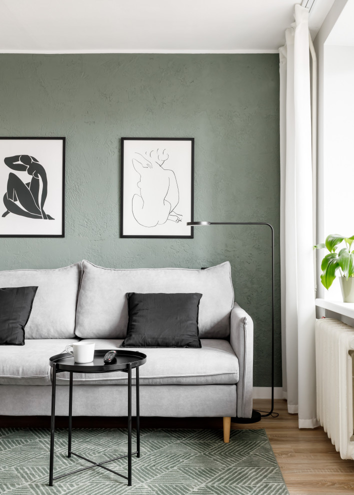 Immagine di un piccolo soggiorno design aperto con pareti verdi, pavimento in laminato, TV autoportante e pavimento marrone